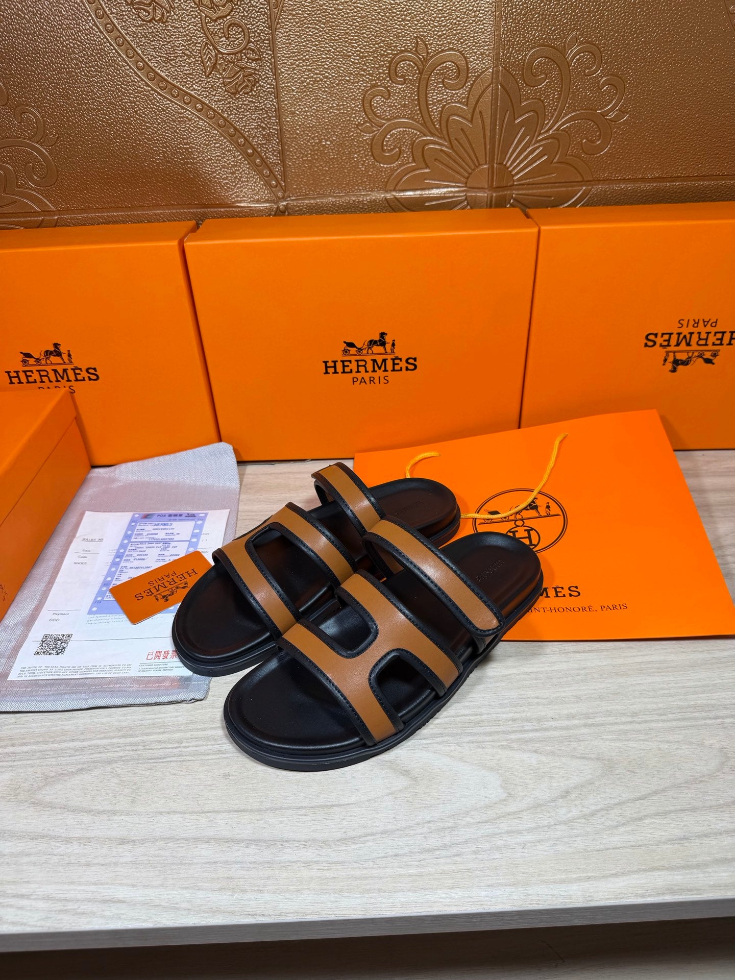 Black and tan slide sandals with two cutout straps and cushioned footbed
