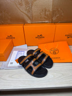Black and tan slide sandals with two cutout straps, shown from the side