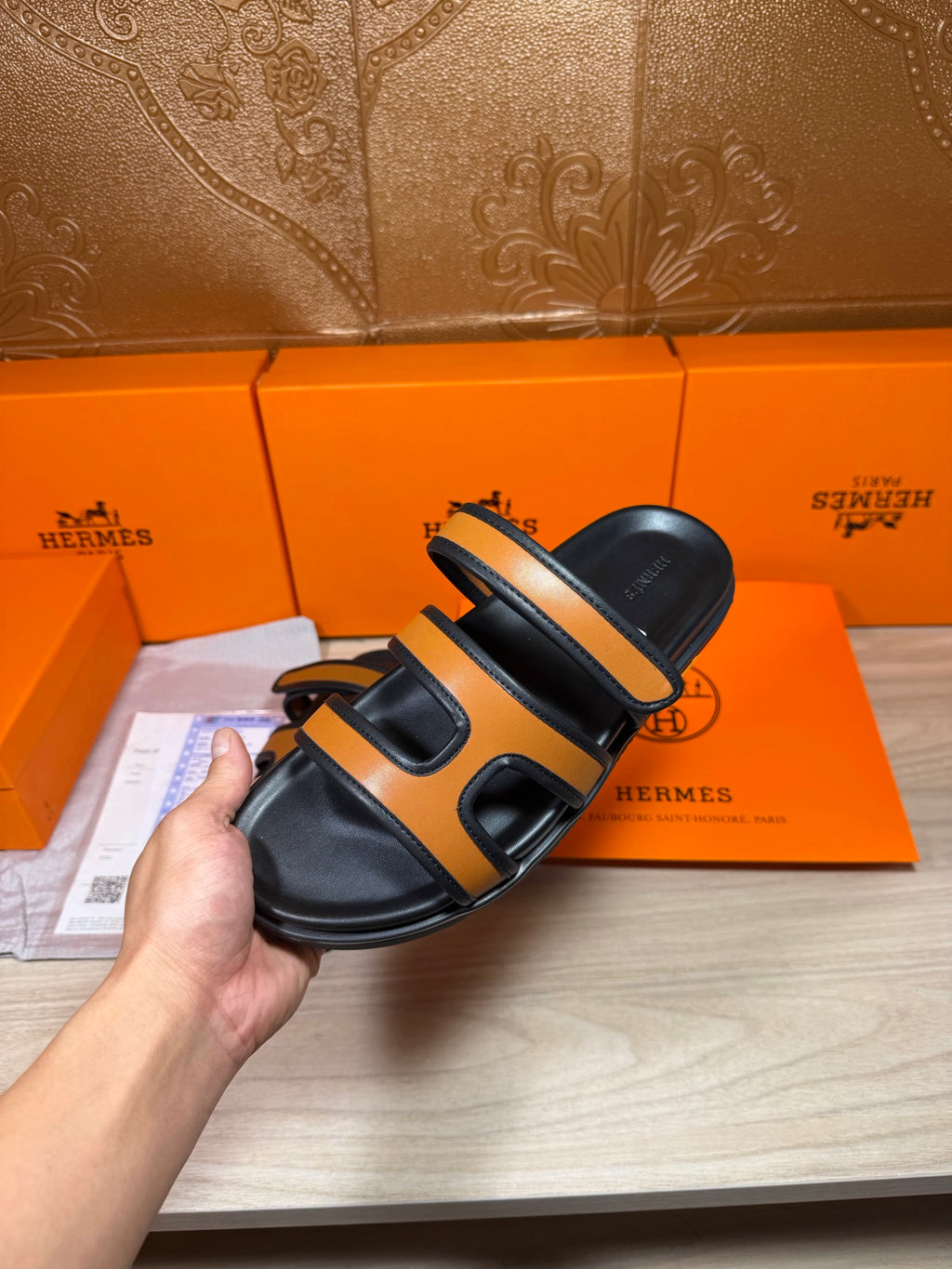 Black and tan slide sandal held to show side straps and cushioned sole