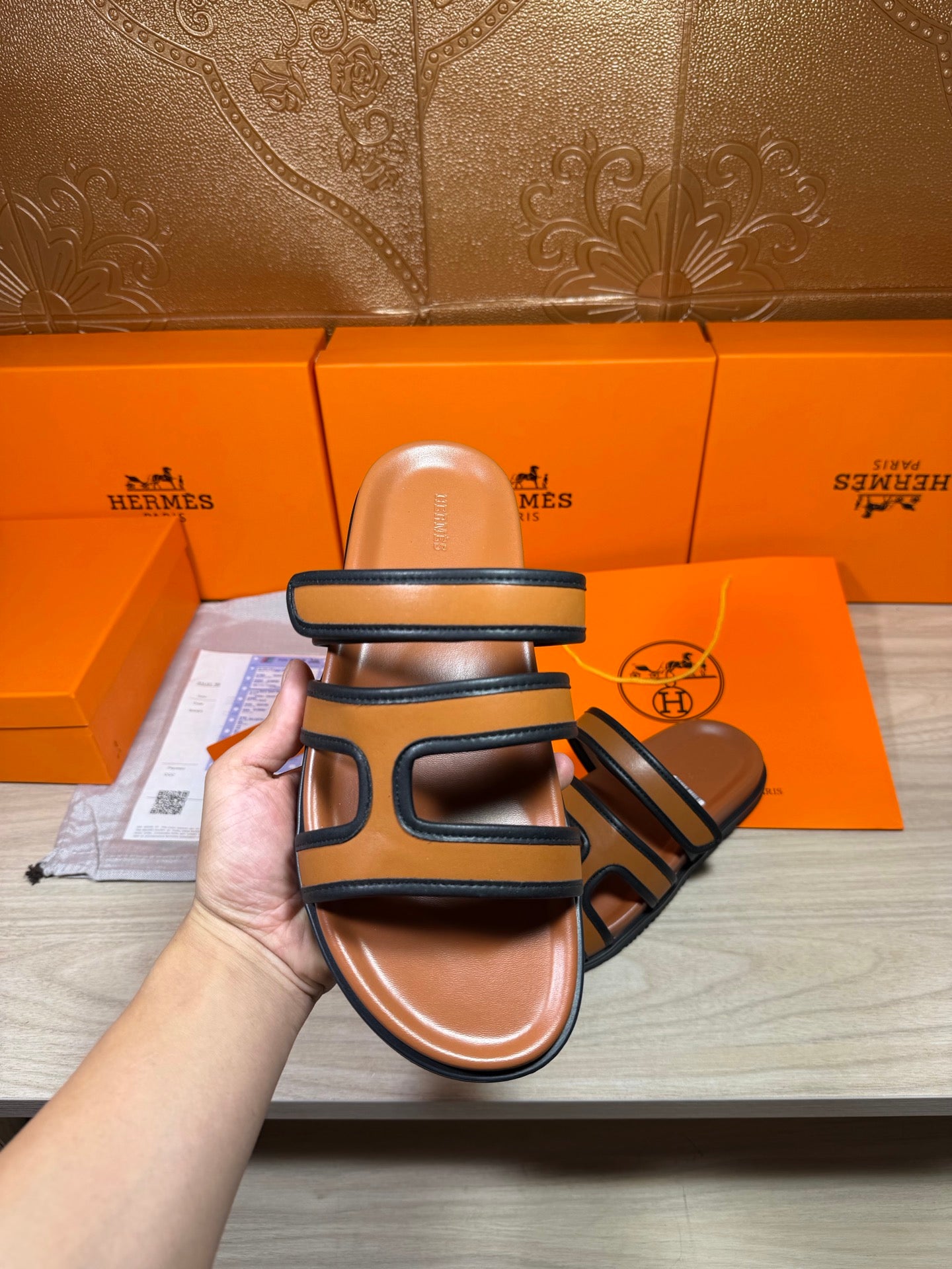 Hermes slide sandals held up, dark blue straps over tan footbed, close view