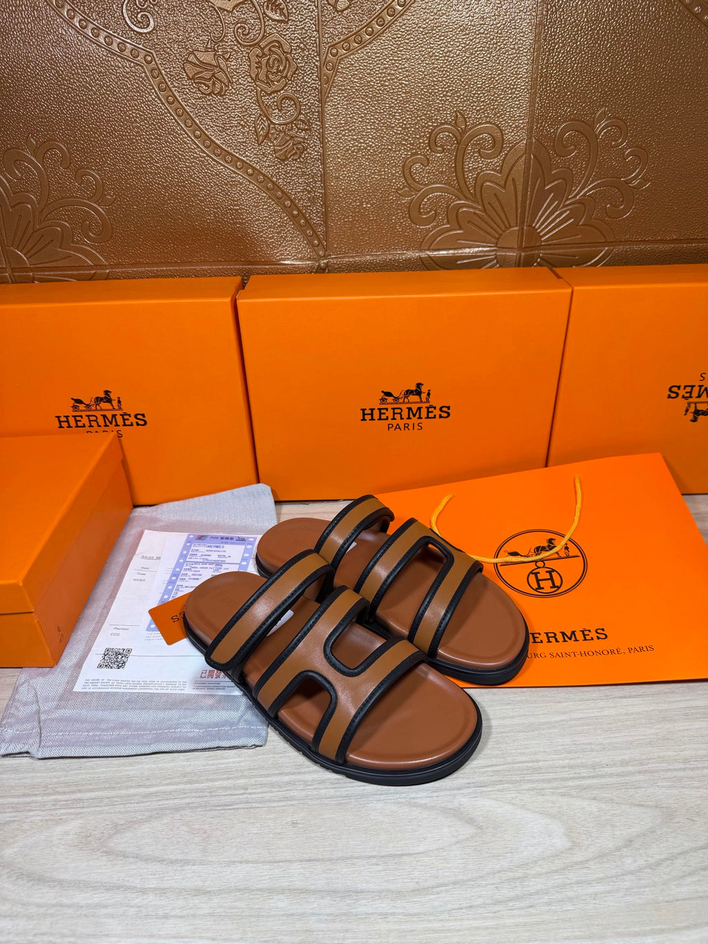 Hermes slide sandals with dark blue straps and tan footbeds, angled view