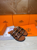 Hermes slide sandals with dark blue straps and tan footbeds, angled view