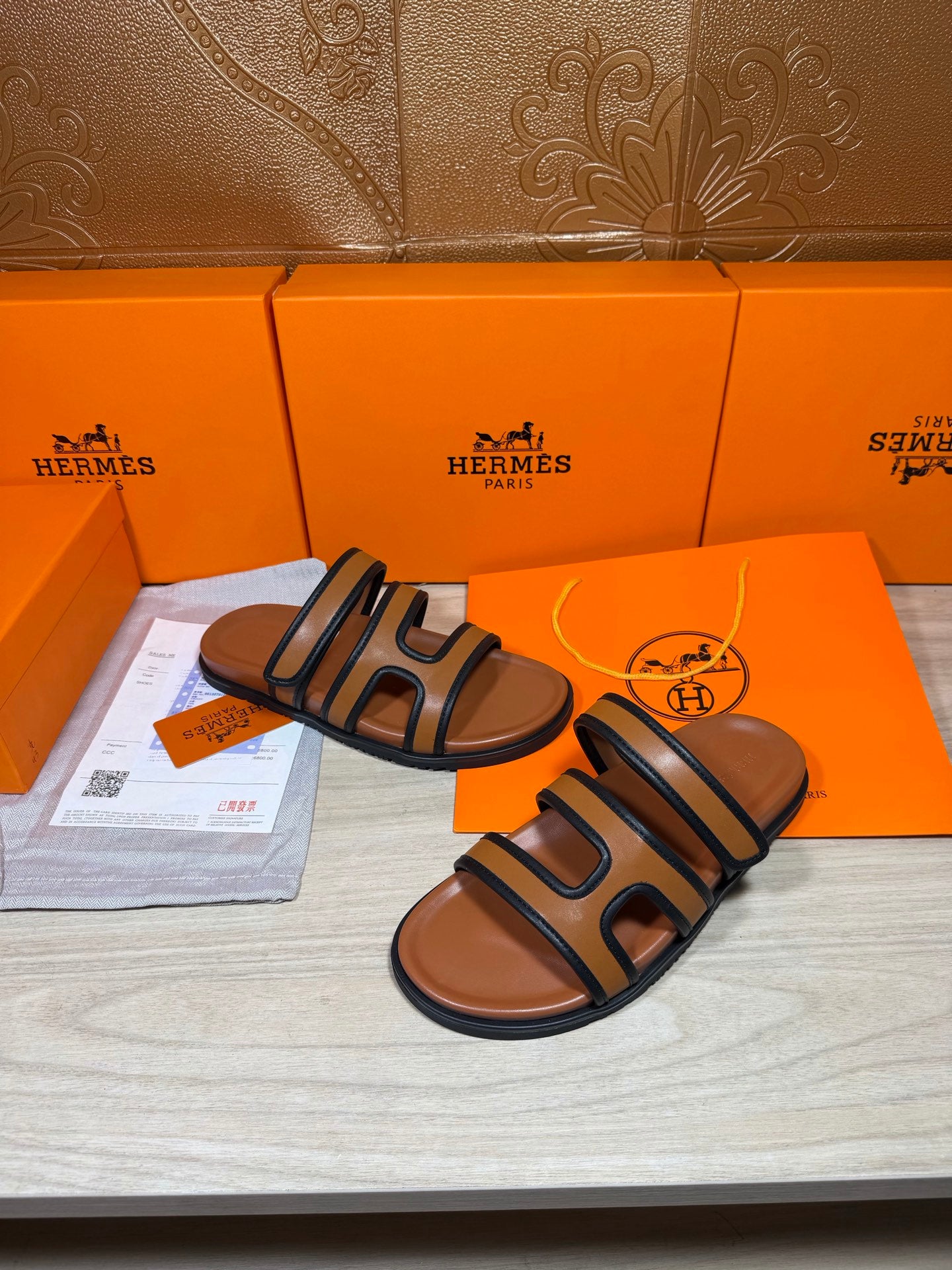 Hermes slide sandals with dark blue straps and tan footbeds, showing open toe