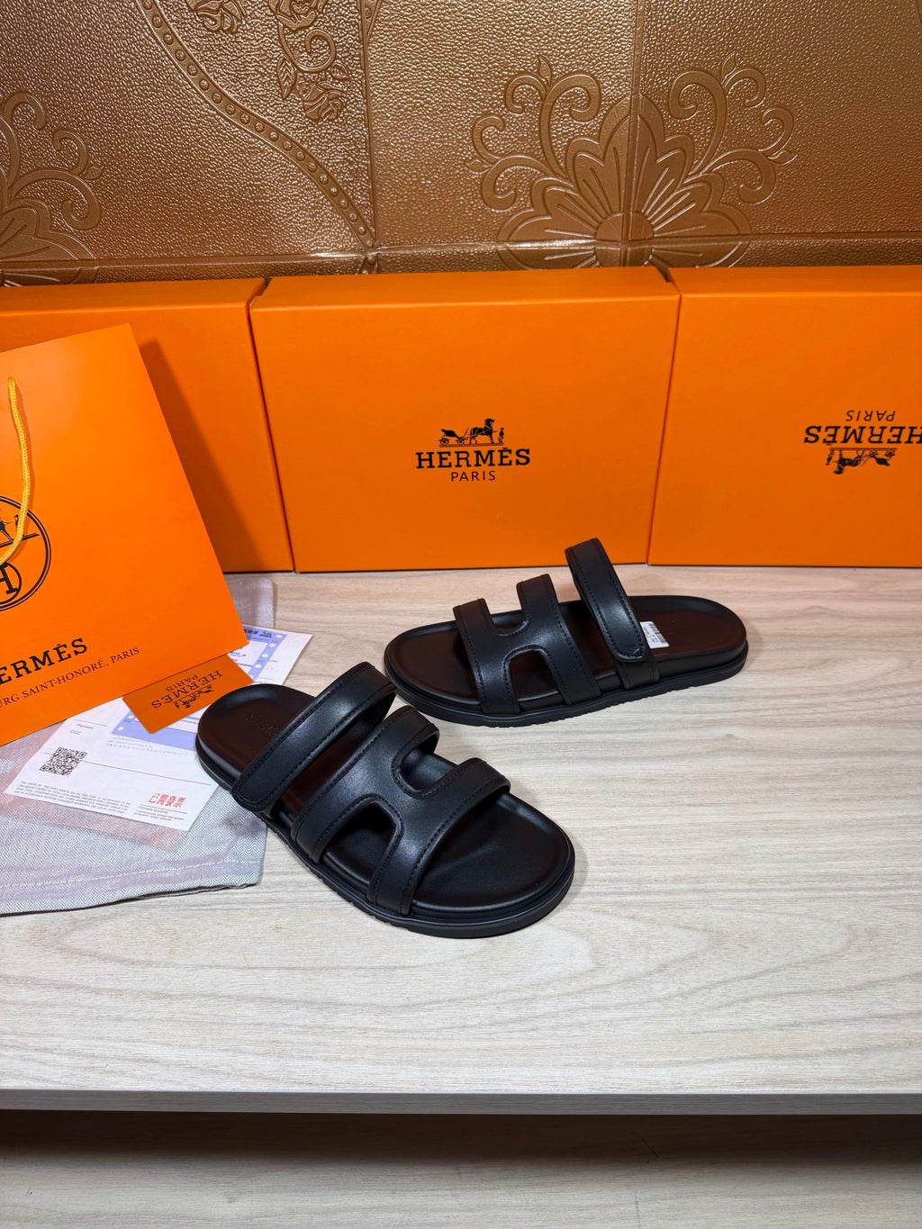 Hermes slide sandals in dark leather, showing two strap details over the foot