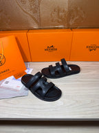 Hermes slide sandals in dark leather, showing two strap details over the foot