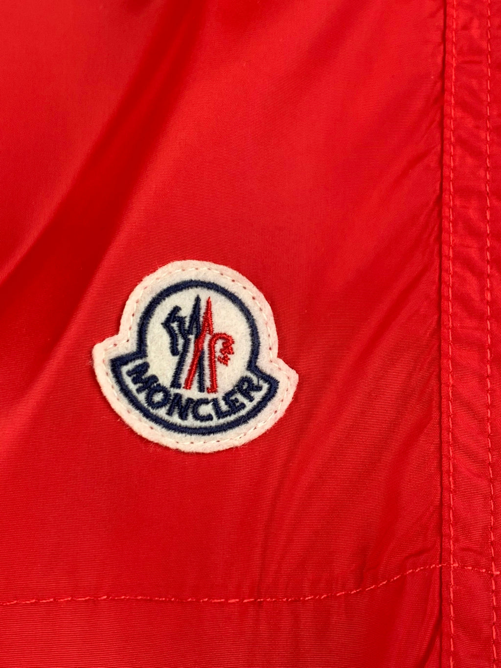 Moncler logo patch on red shorts with embroidered crest and text