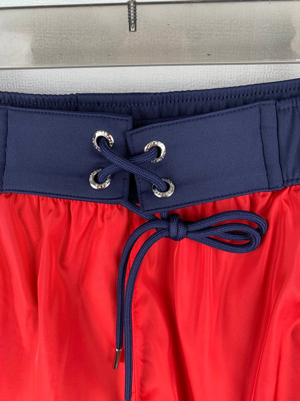 Moncler red shorts with navy drawstring, lace-up eyelets, and elastic waistband