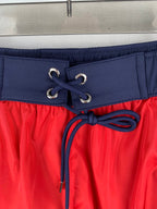 Moncler red shorts with navy drawstring, lace-up eyelets, and elastic waistband