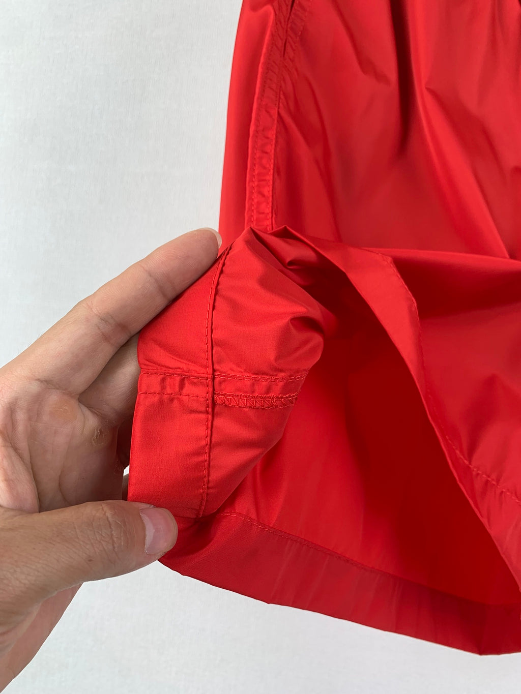 Moncler red shorts; hand highlights fabric panels and pocket seam detail