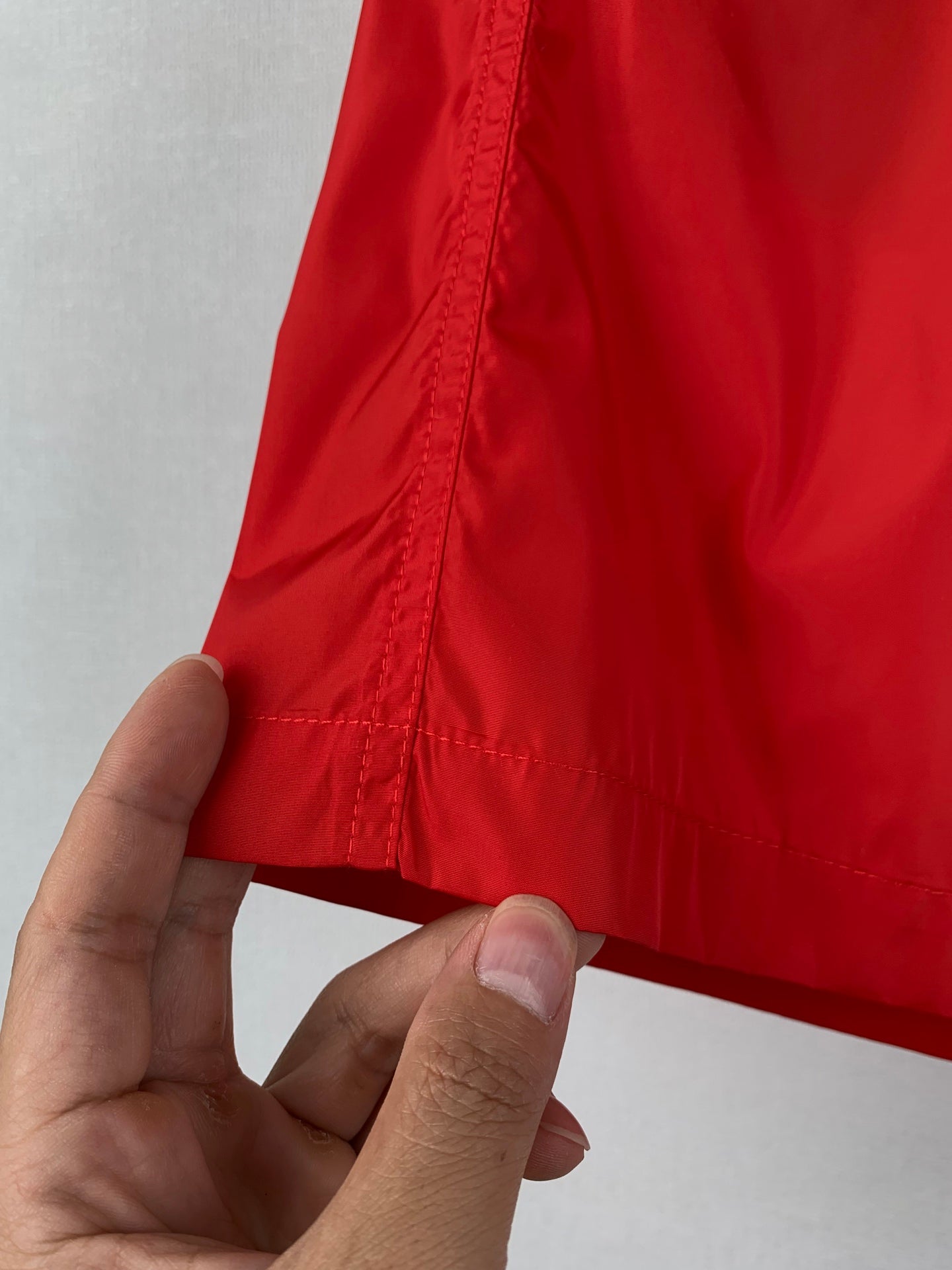 Moncler red shorts; hand shows side seam stitching on the leg