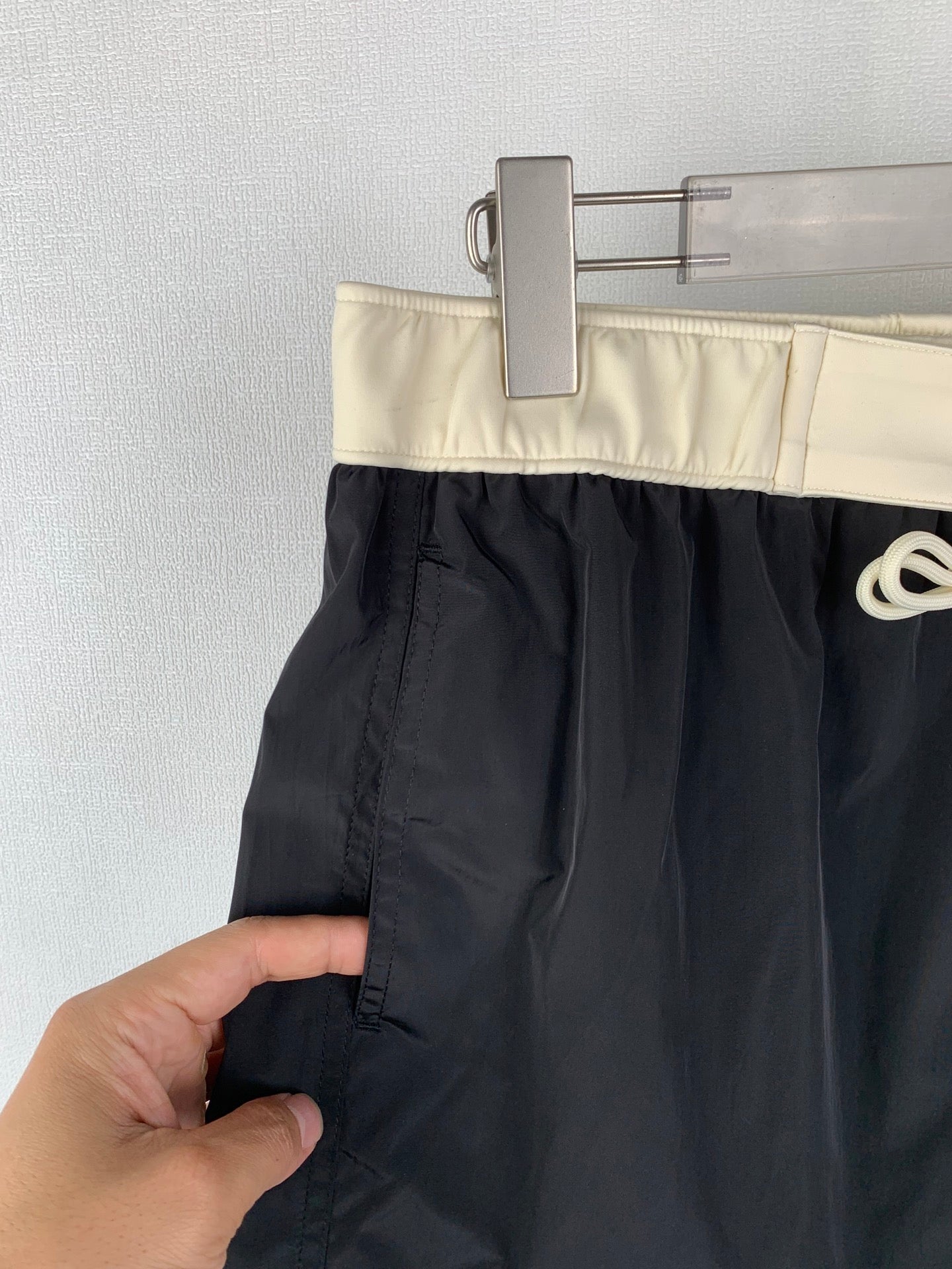 Moncler black swim shorts held at the front seam with pocket panel visible