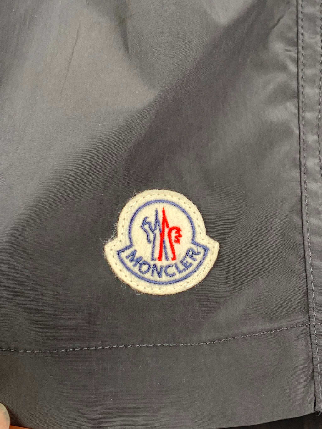 Moncler logo patch on black swim shorts fabric close-up