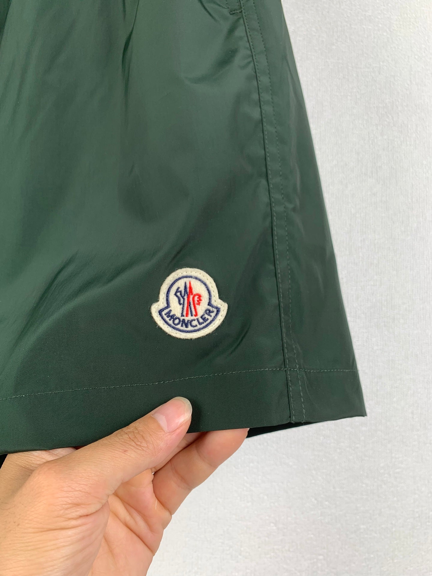 Moncler green shorts with stitched hem and logo patch on leg