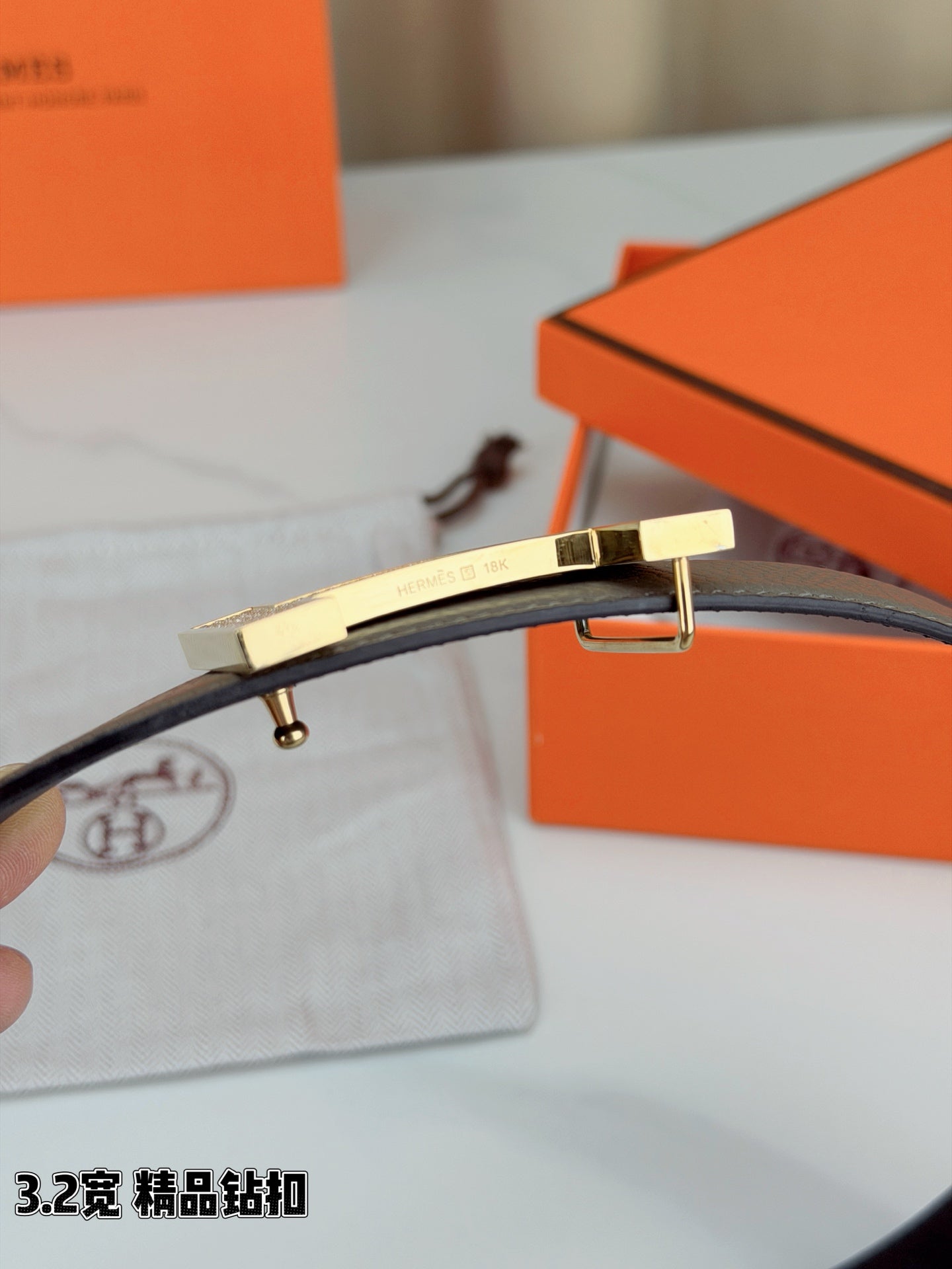 Hermes belt end with gray strap and gold-tone H buckle clasp, prong visible