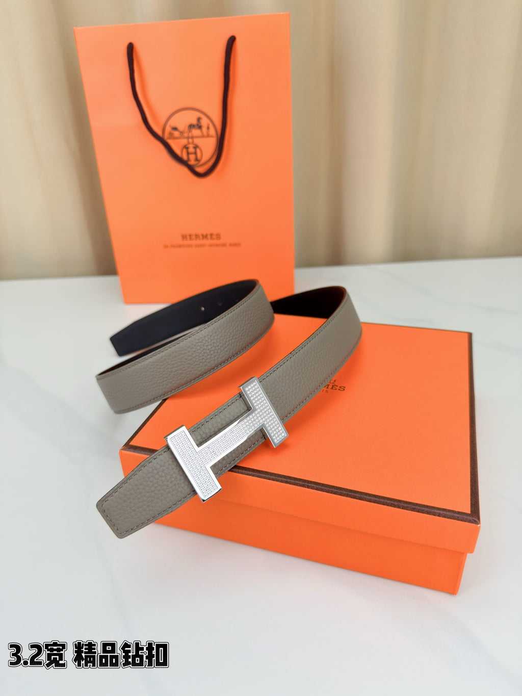 Hermes leather belt set with gray strap and silver-tone H buckle on orange boxes