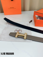 Hermes belt with dark leather strap and gold-tone H buckle on display