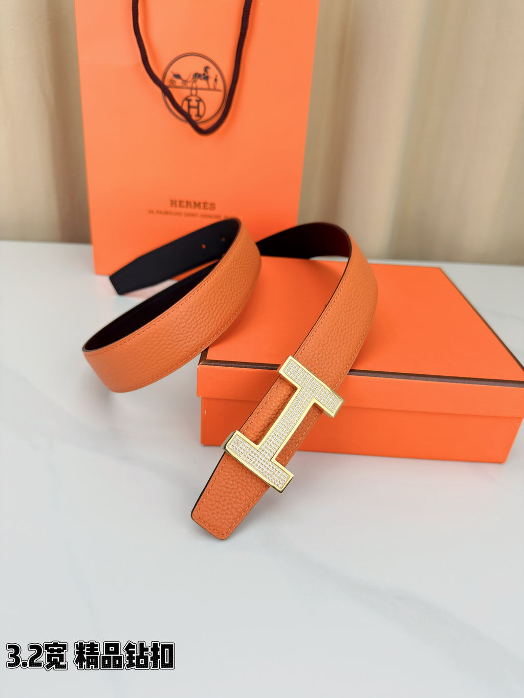 Hermes belt with orange strap, silver H buckle, and matching dark inner strap