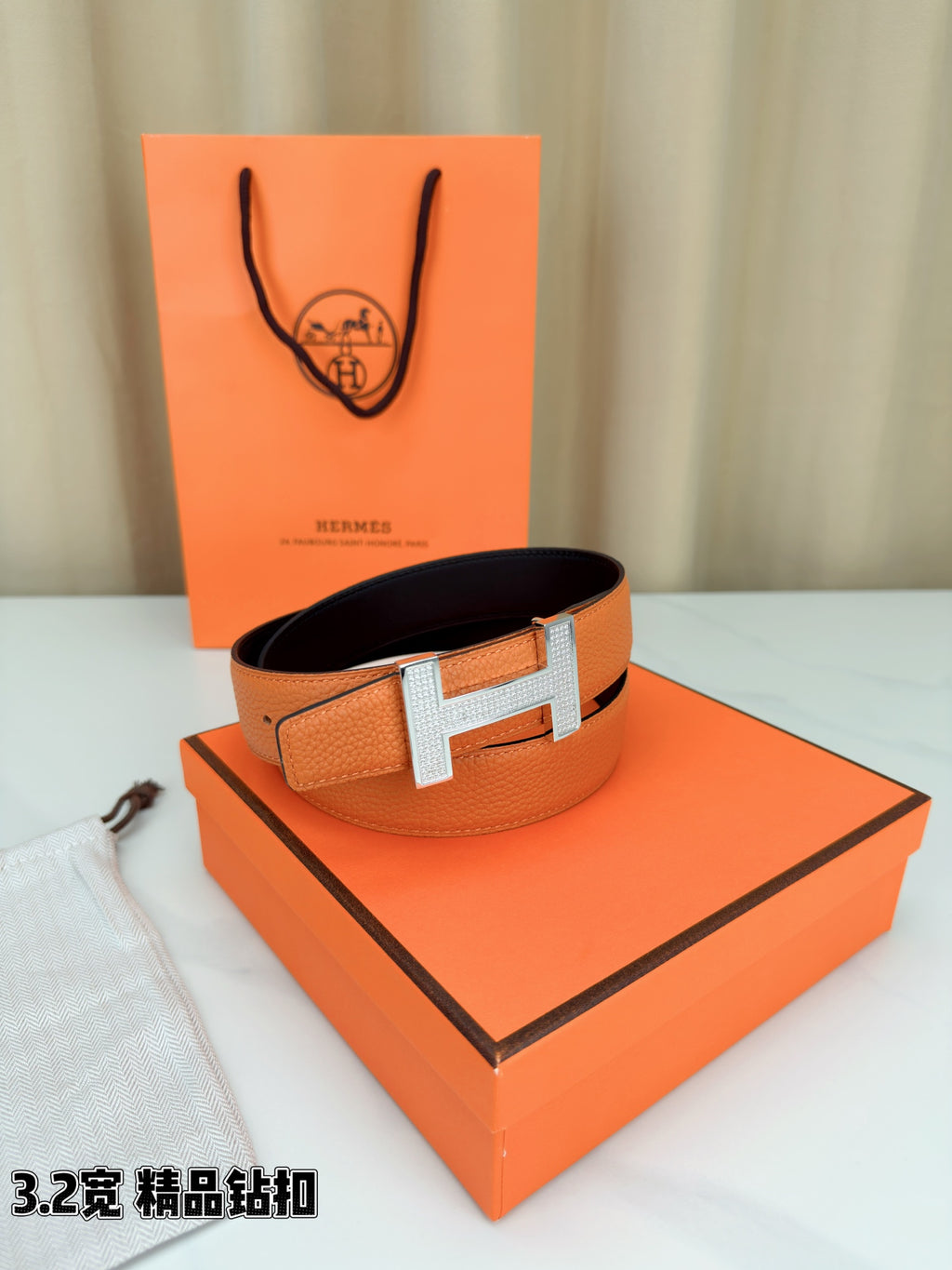Hermes belt with orange leather and silver H buckle, angled view