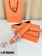 Hermes belt with orange leather strap, silver H buckle, and dark inner band