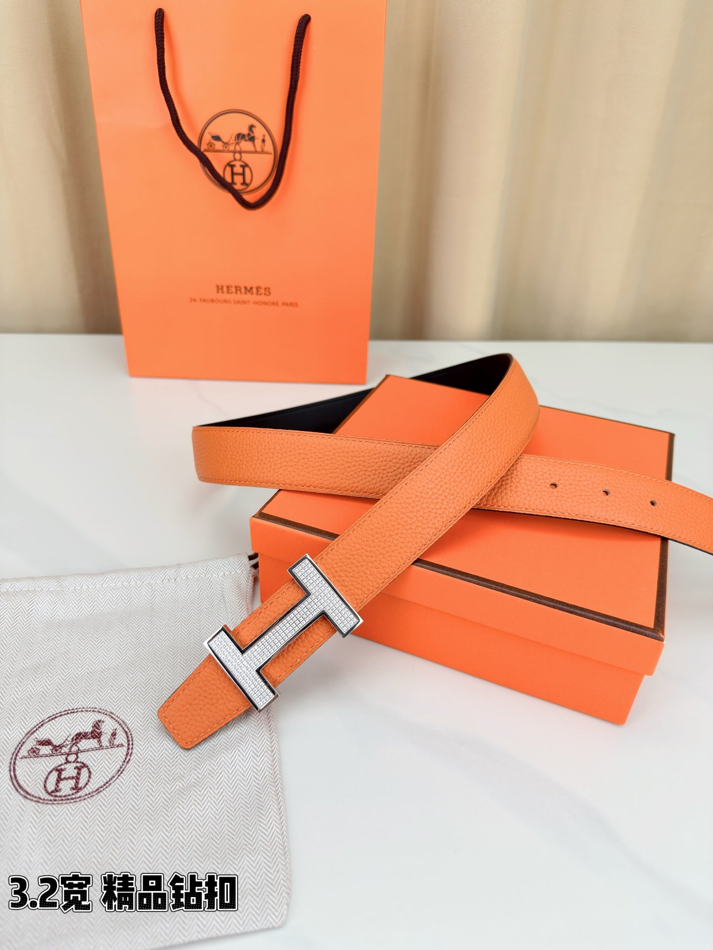 Hermes belt with orange leather strap, silver H buckle, and dark inner band