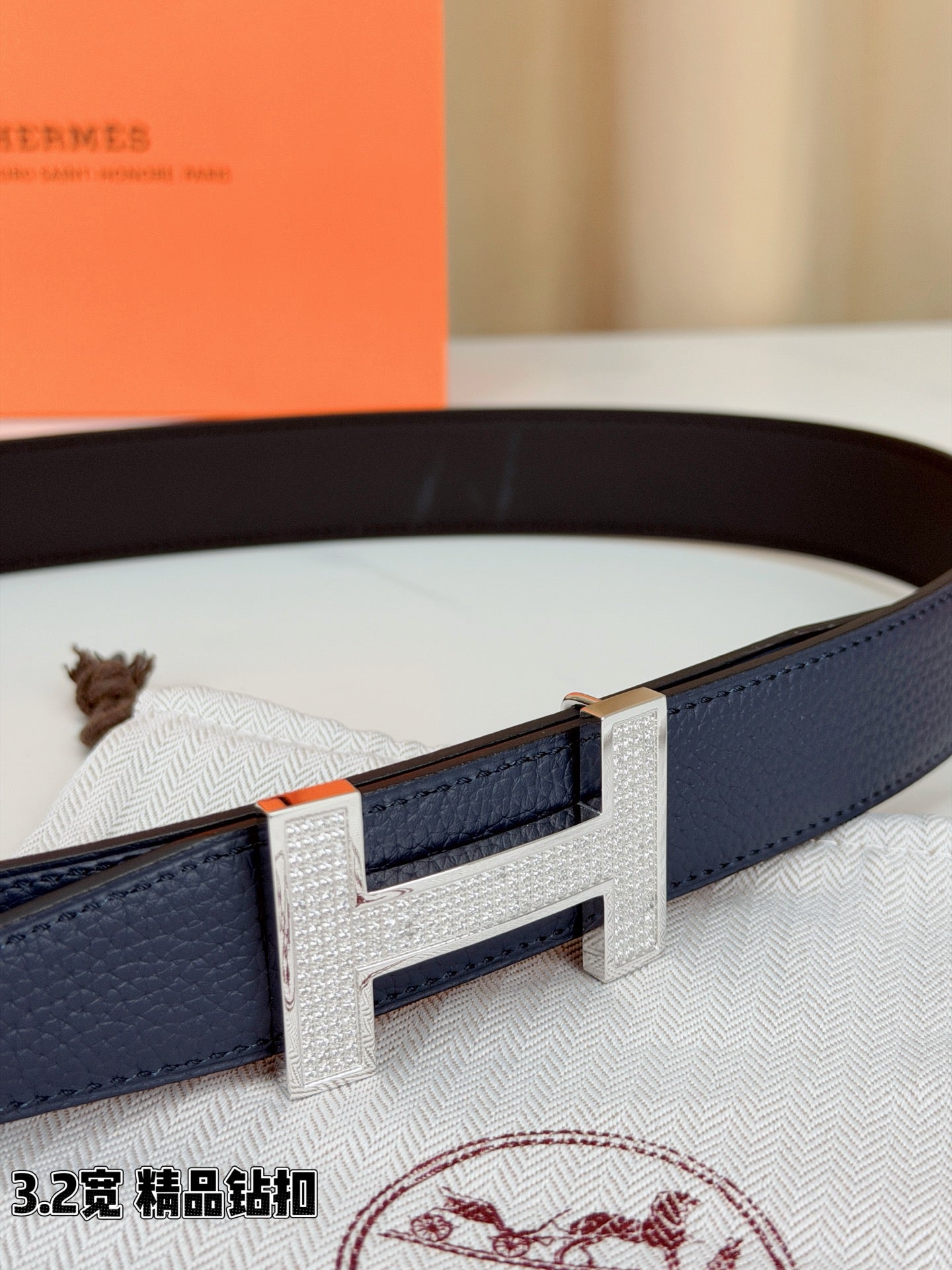 Blue leather belt with silver-tone H buckle, textured strap edge detail