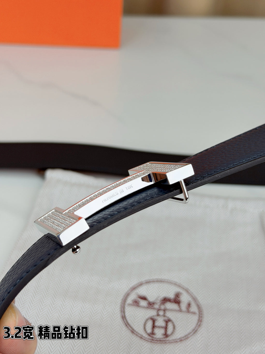 Blue leather belt with silver-tone H buckle close-up on textured strap