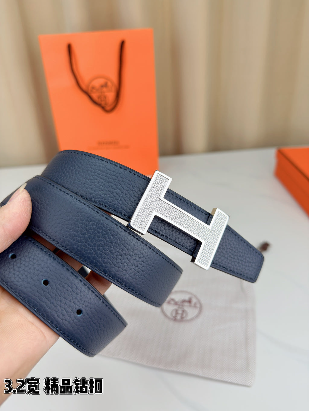 Blue leather belt with silver-tone H buckle and visible belt holes