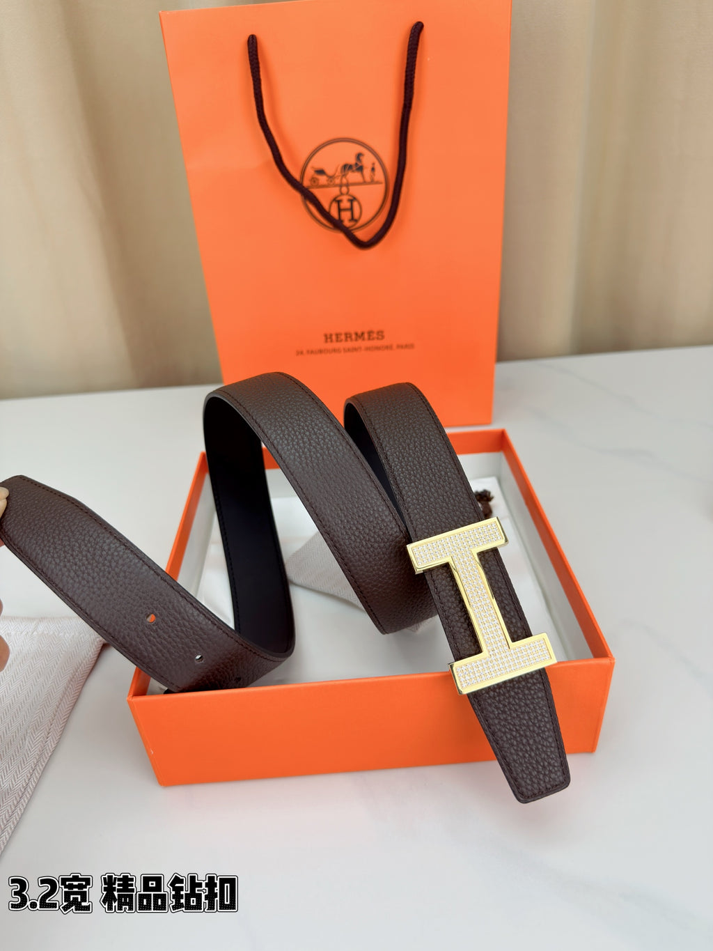 Dark brown leather belt with gold-tone H buckle shown at an angle