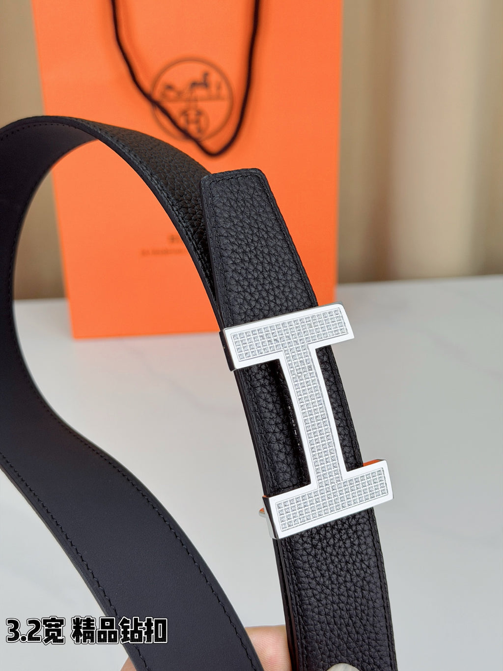 Hermes belt close-up: dark textured leather strap with silver-tone H buckle