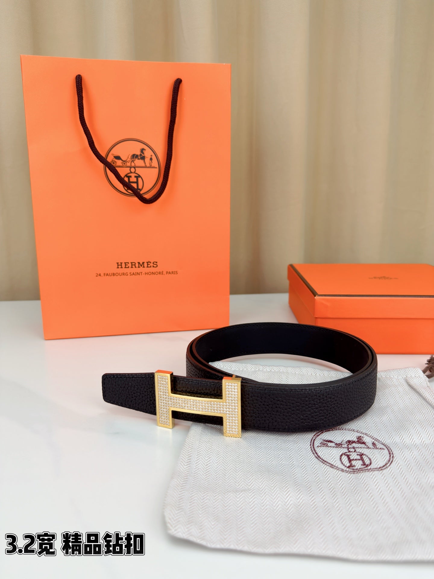 Hermes belt with dark leather strap and silver-tone H buckle, paired with dust bag