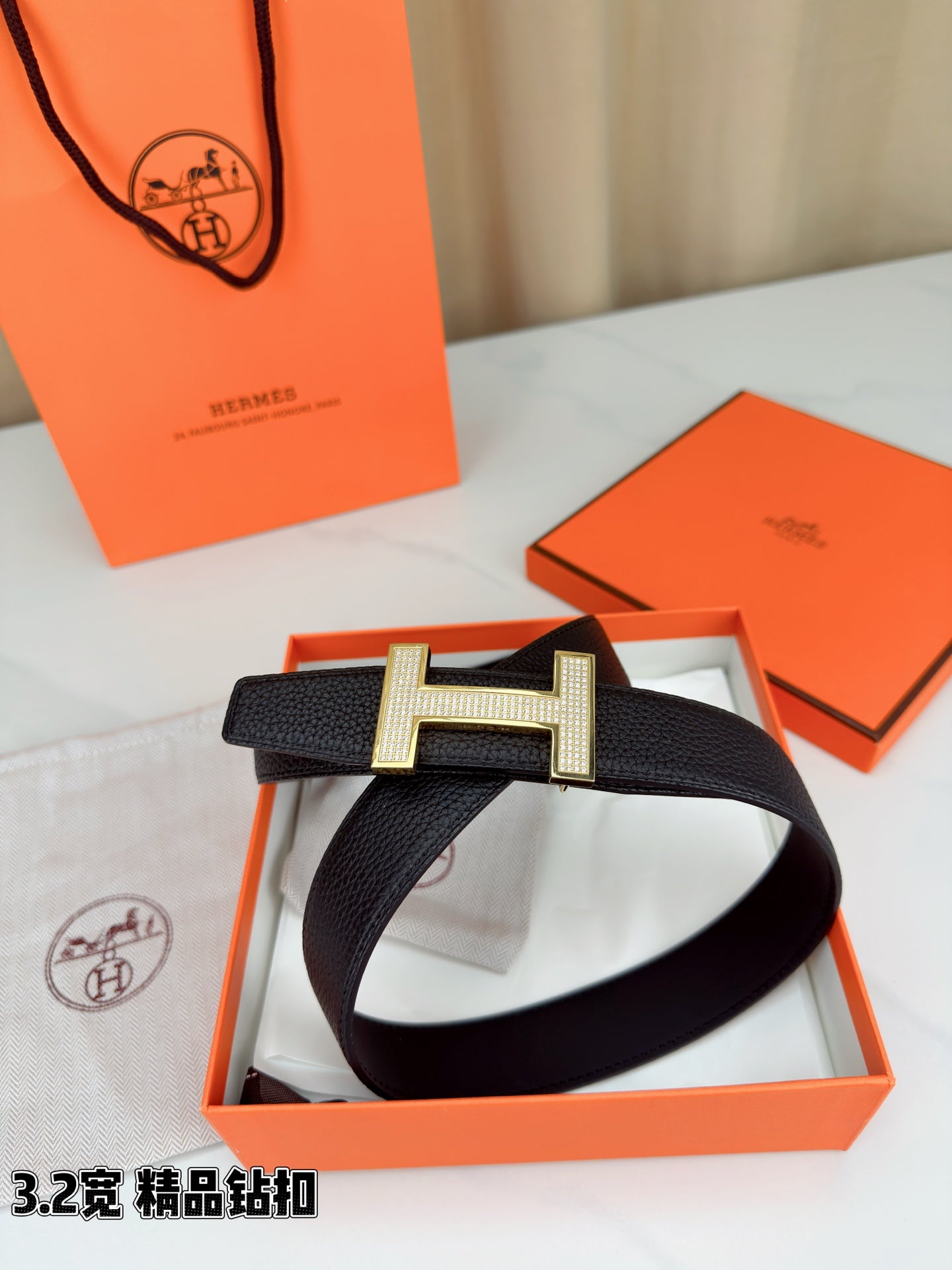 Hermes belt with dark textured leather strap and silver-tone H buckle on gift box
