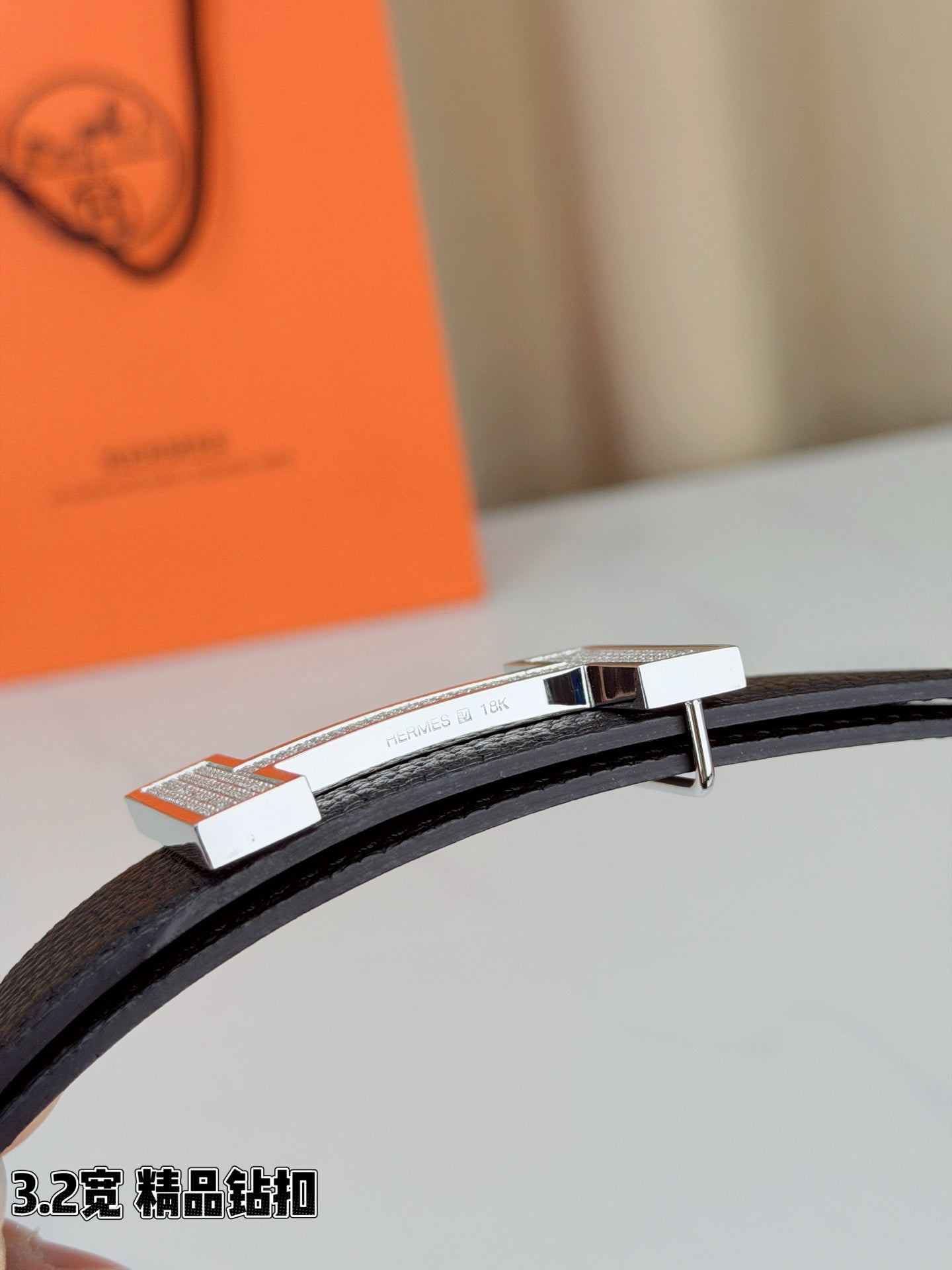 Hermes belt close-up of silver-tone buckle on dark leather strap