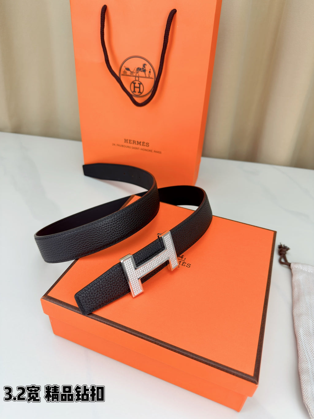 Hermes belt with dark leather strap and silver-tone H buckle, displayed with box