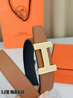 Close-up of tan belt with silver H buckle on pebble-grain leather strap