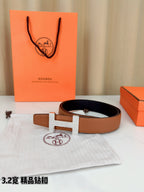 Tan leather belt with silver H buckle, laid flat with box and dust bag nearby