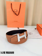 Tan leather belt with silver H buckle, shown coiled with black-lined interior