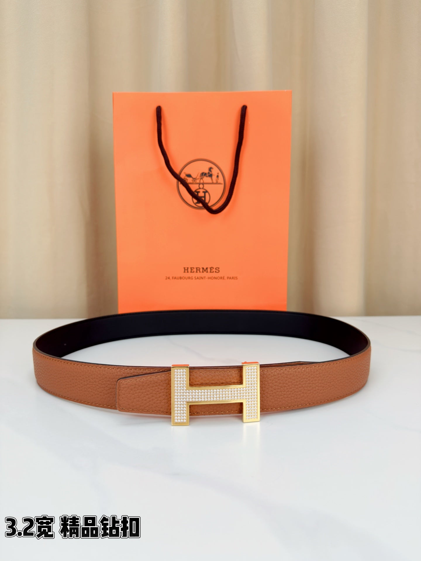 Tan leather belt with silver-tone H buckle and dark inner lining edge