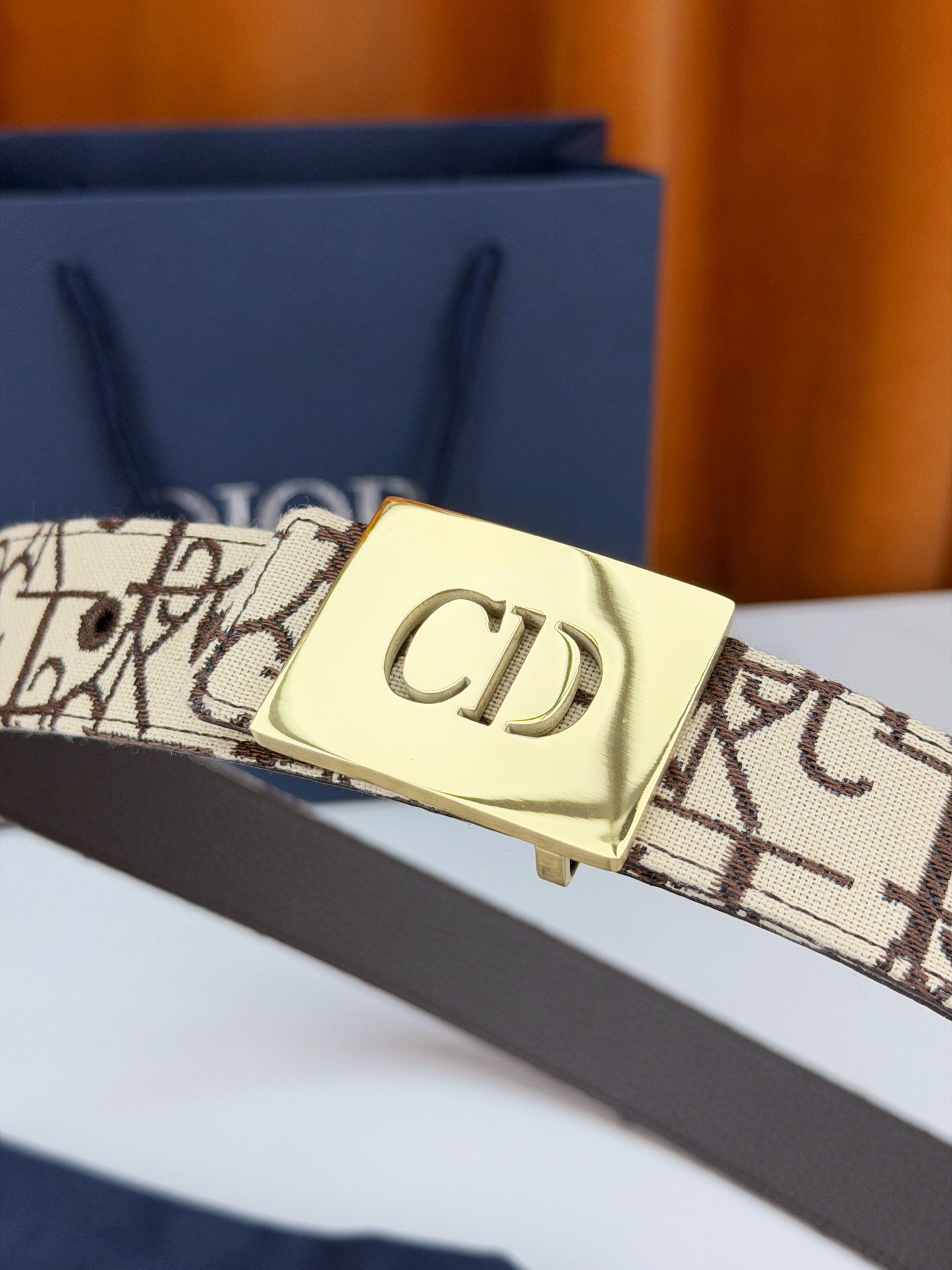 Dior belt close-up with beige monogram strap and gold-tone 'CD' buckle