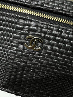 Black woven handbag with Chanel CC logo and gold-tone zipper detail, close-up
