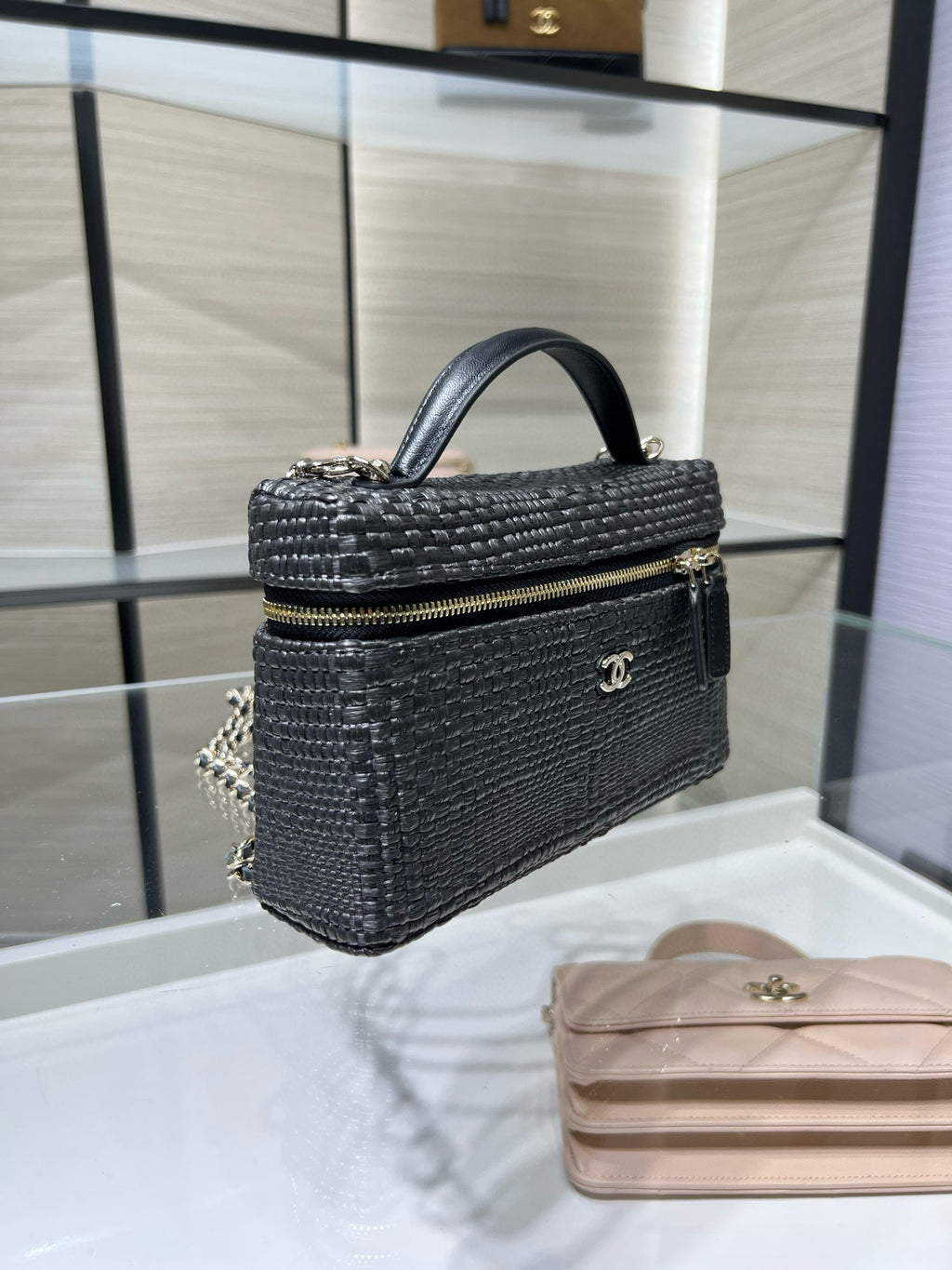Black woven mini handbag with top handle, chain strap, and gold-tone logo plaque