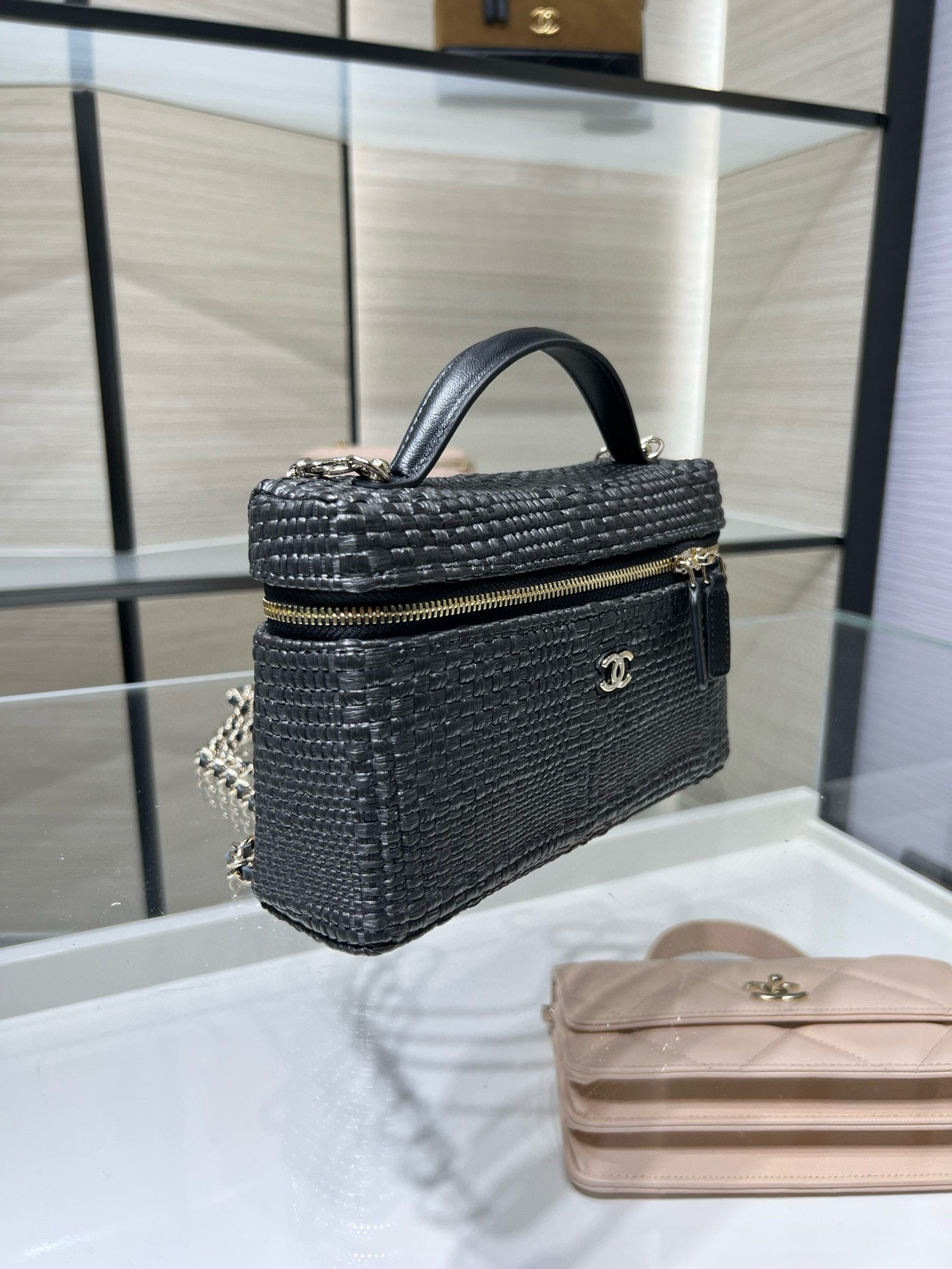 Black woven mini handbag with top handle, chain strap, and gold-tone logo plaque