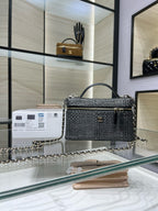 Black woven top-handle handbag with chain strap and gold-tone hardware, front flap