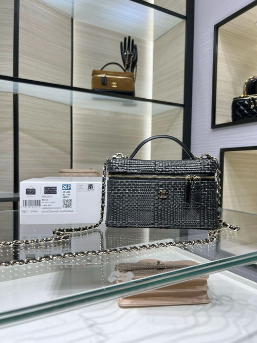 Black woven top-handle handbag with chain strap and gold-tone hardware, front flap