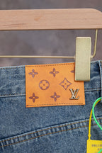 Blue denim jeans with orange monogram patch and Louis Vuitton logo on back pocket.
