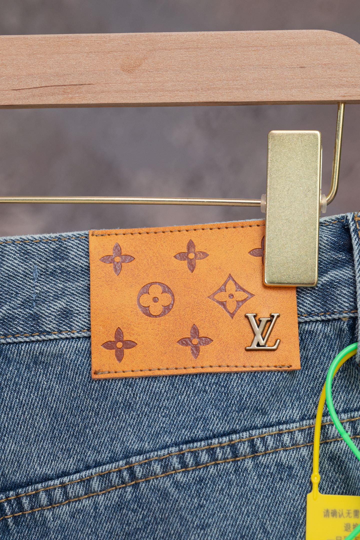 Blue denim jeans with orange monogram patch and Louis Vuitton logo on back pocket.