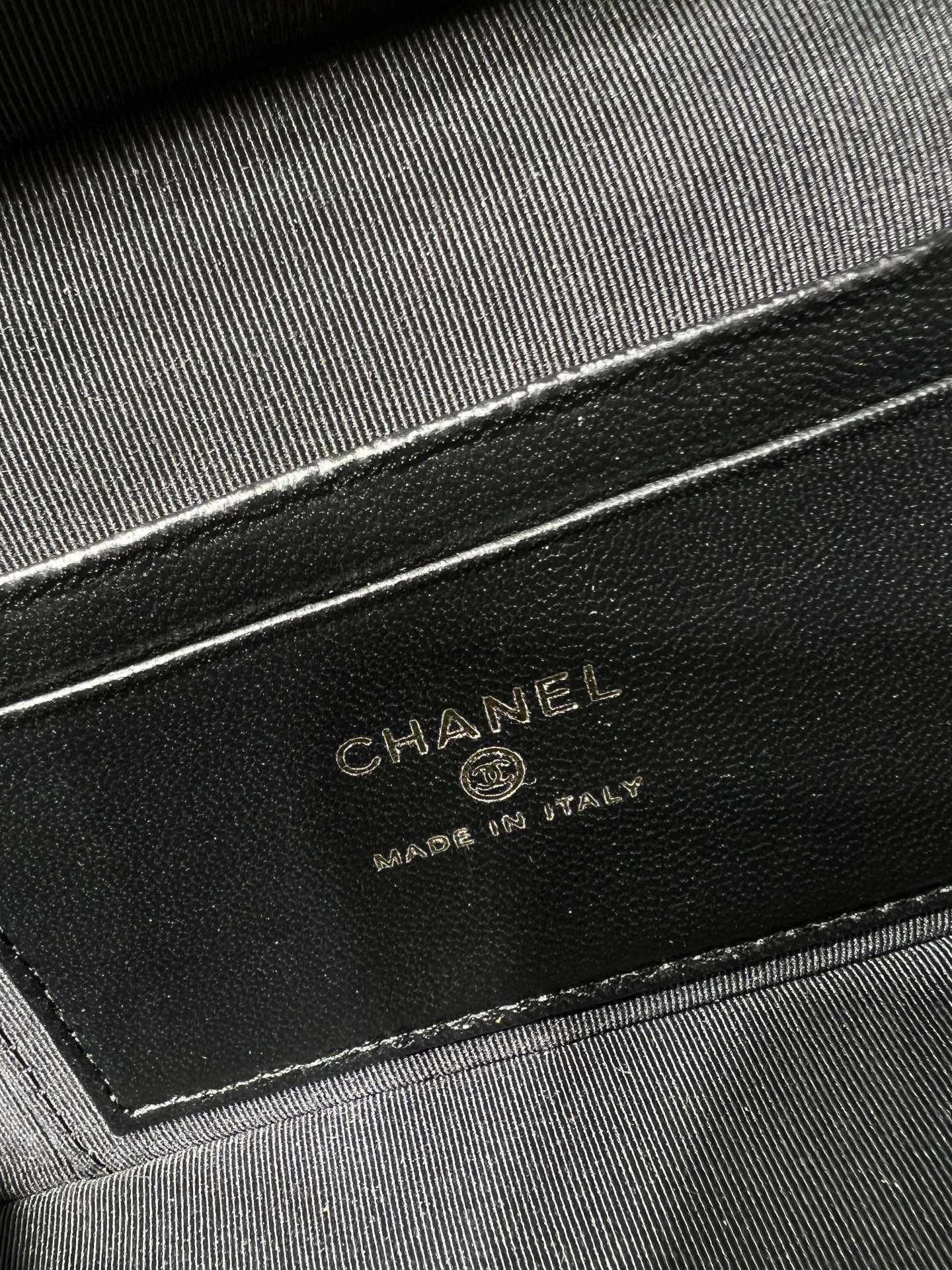 Close-up of black Chanel leather label reading CHANEL, made in Italy