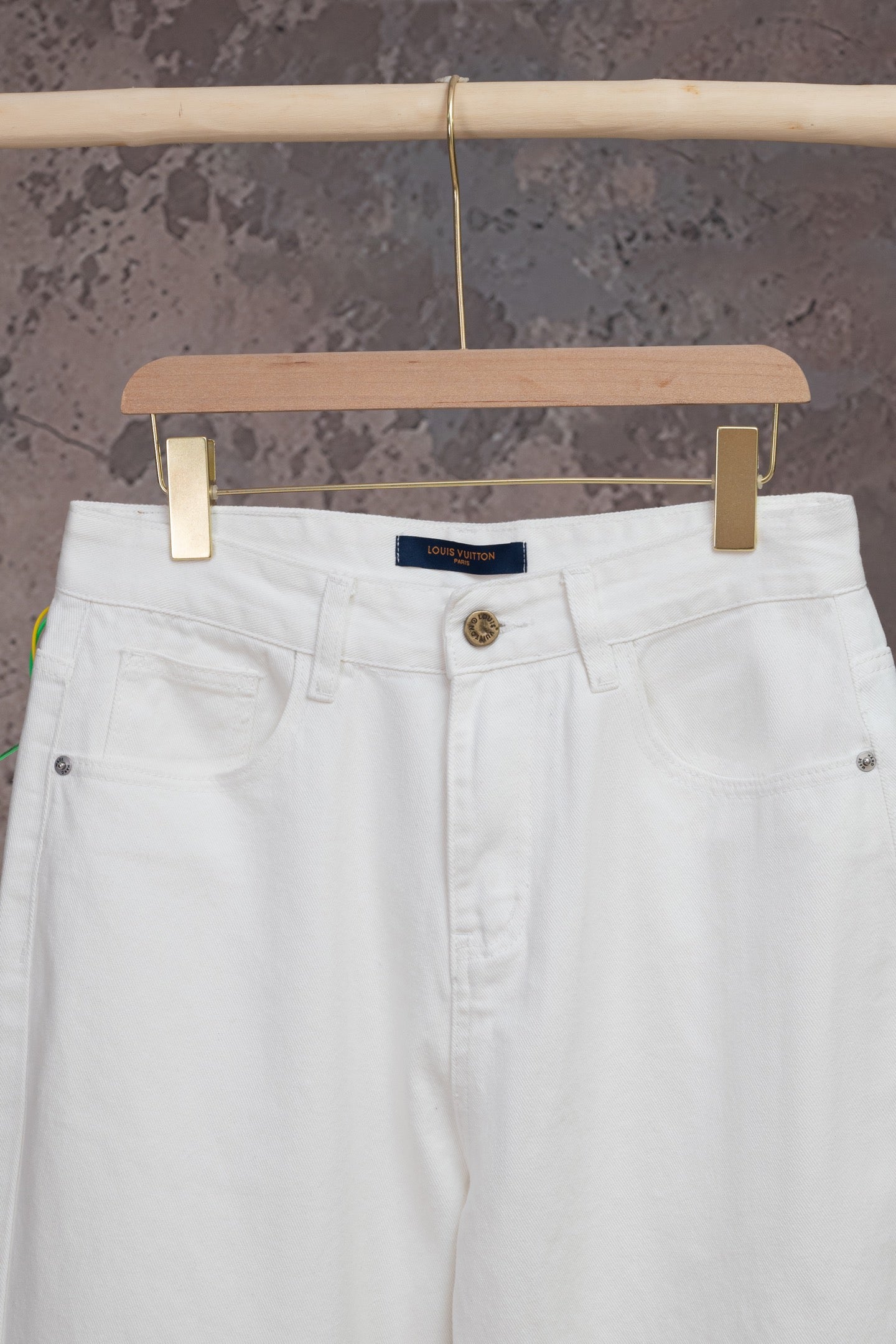 White denim pants front with button closure and waistband logo tag