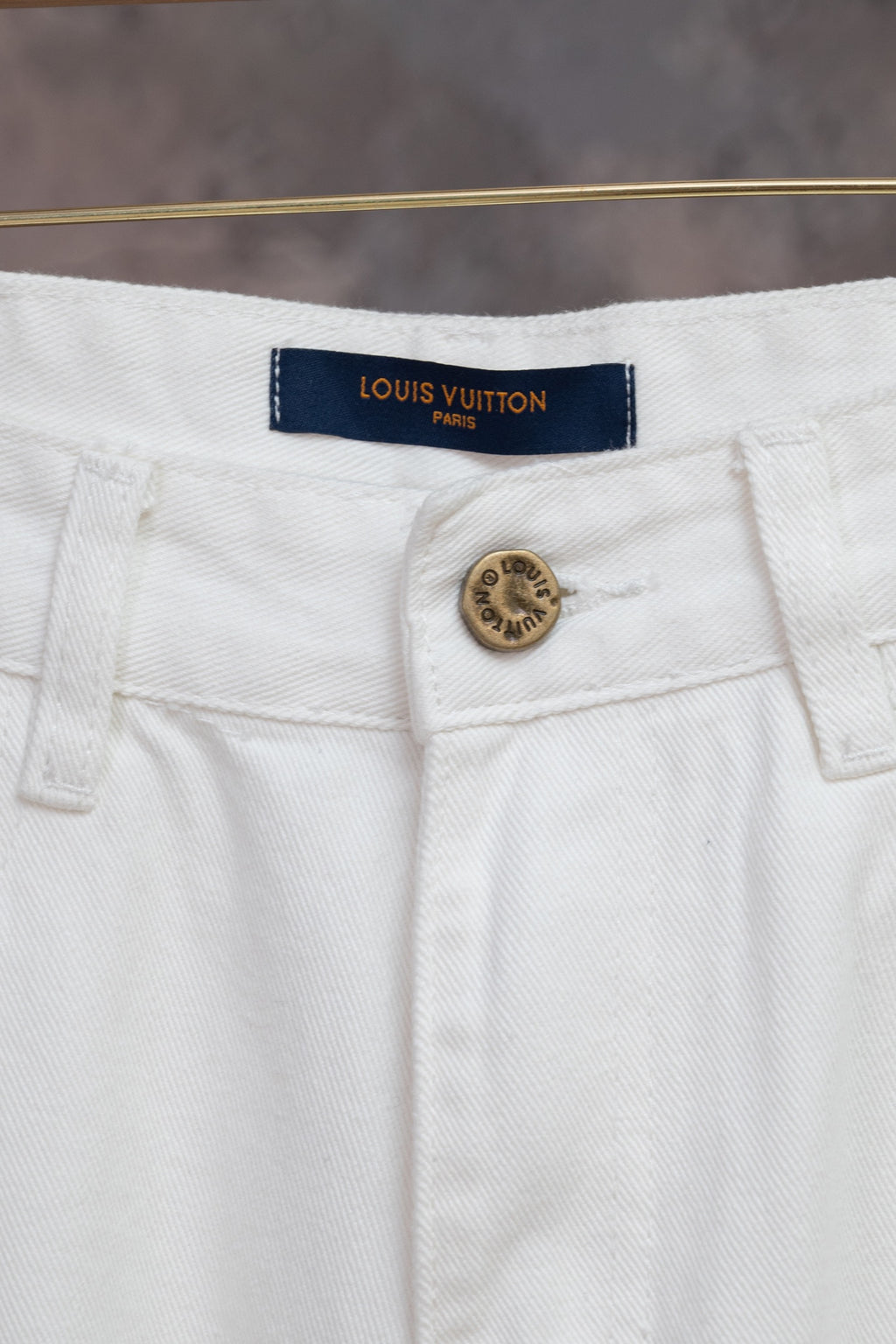 White denim pants waistband with Louis Vuitton logo patch and button