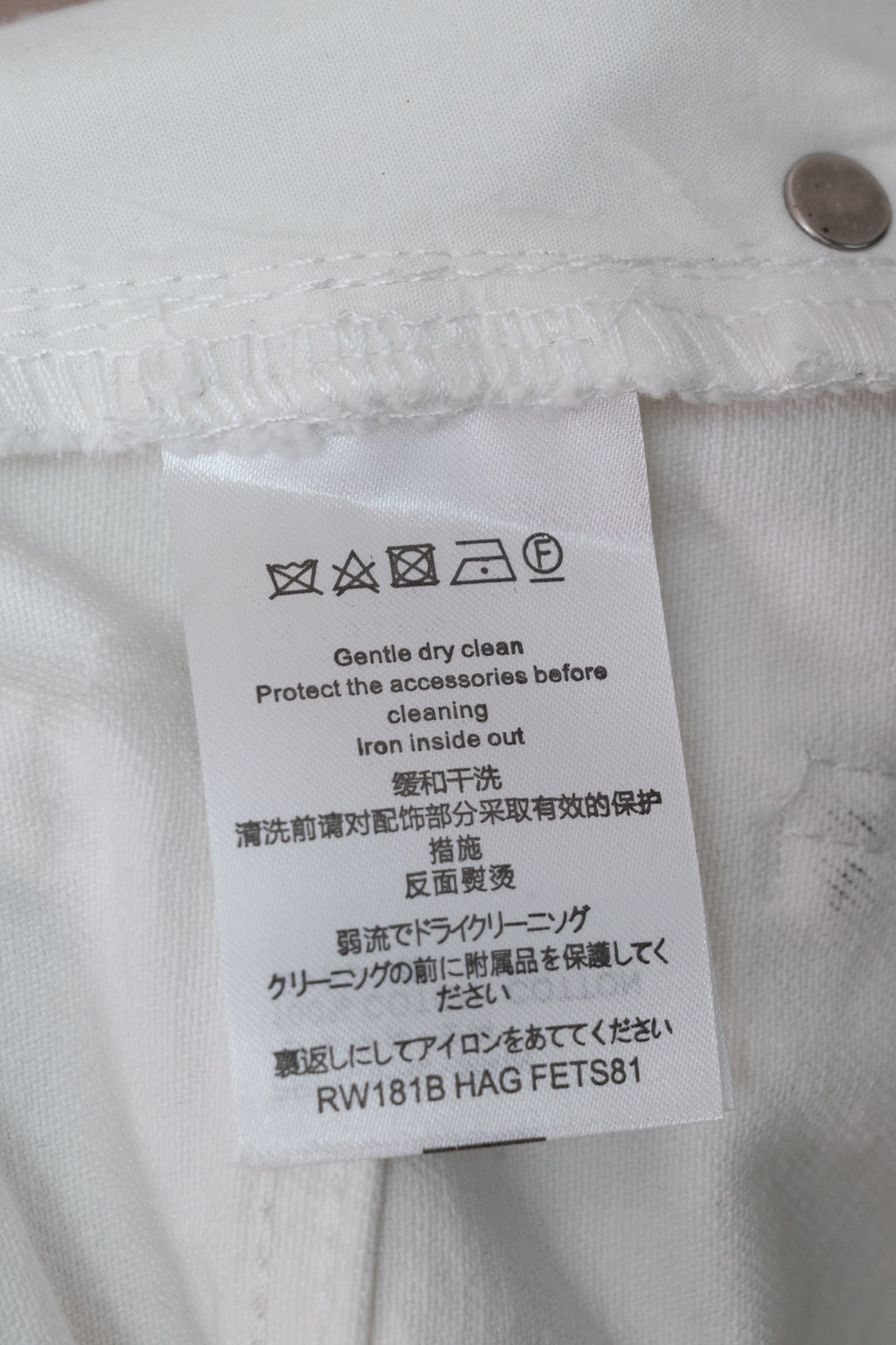 White denim pants care label with washing and ironing instructions
