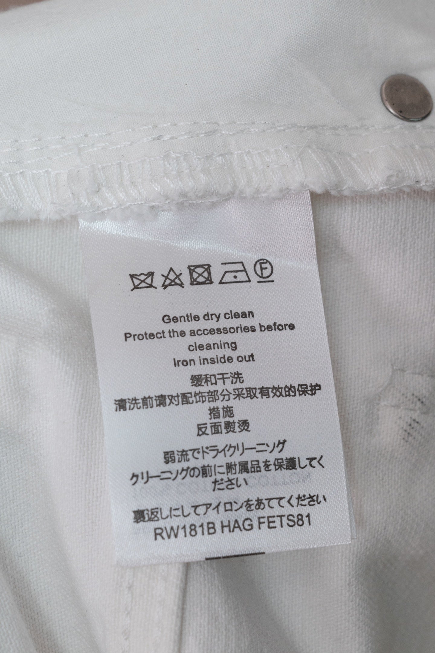 White denim pants care label with washing and ironing instructions